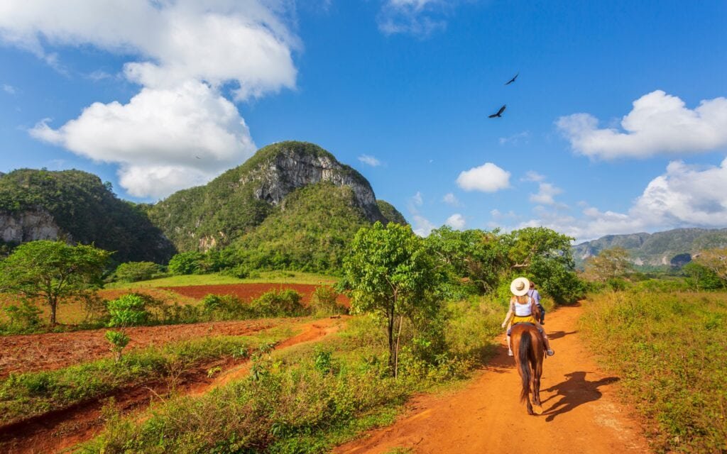 Turisté na prohlídce na koni v Národním parku Viñales, Kuba.