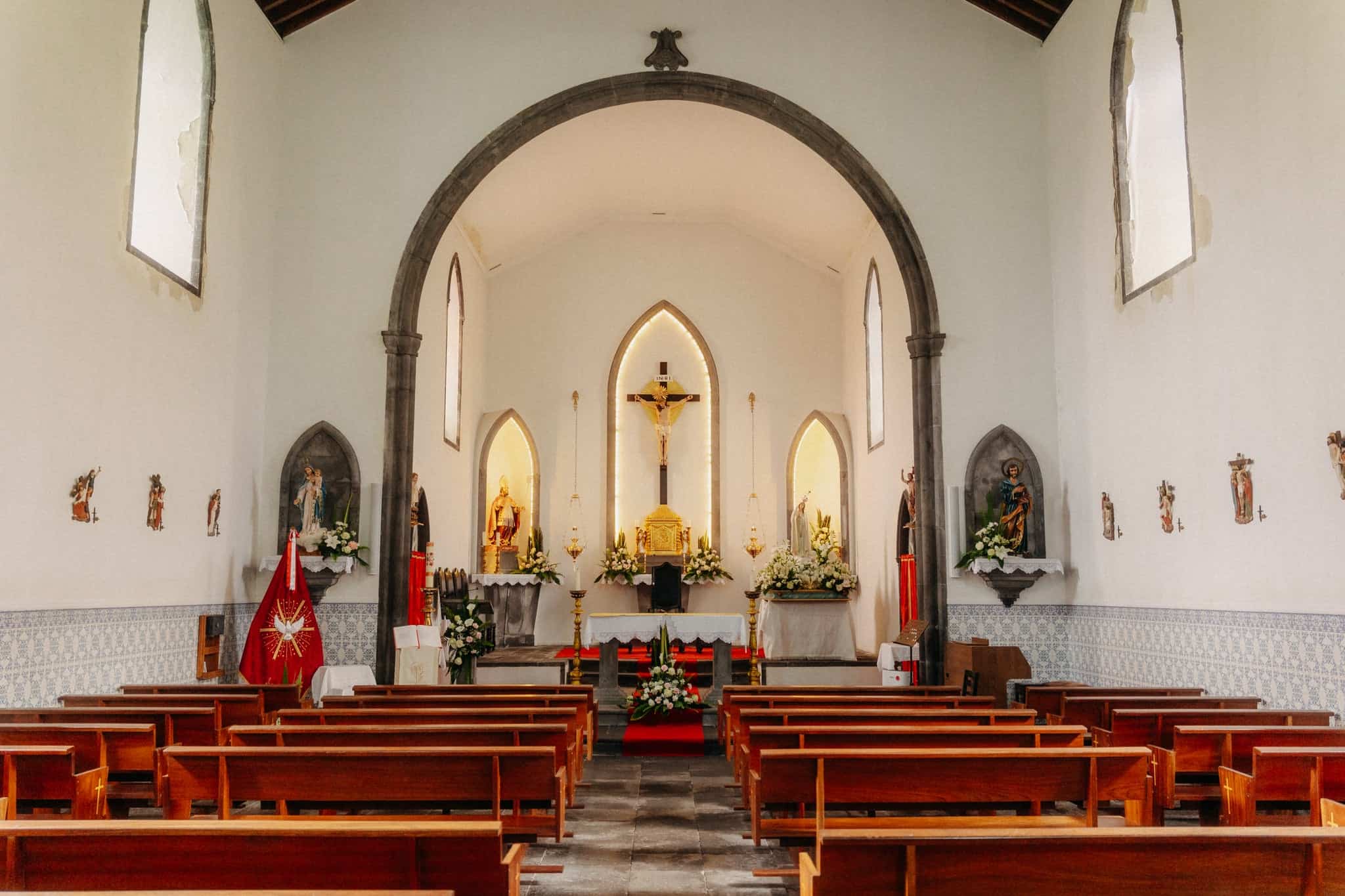 Interiér kostela s dřevěnými lavicemi a zlatým oltářem, Sete Cidades, Sao Miguel