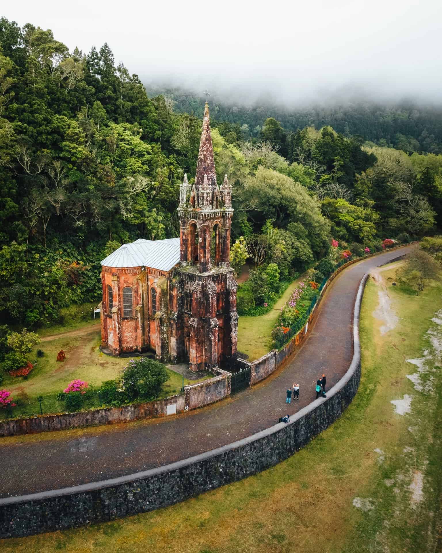 Gotický kostel obklopený tropickou zelení podél klikaté cesty, Furnas, Sao Miguel