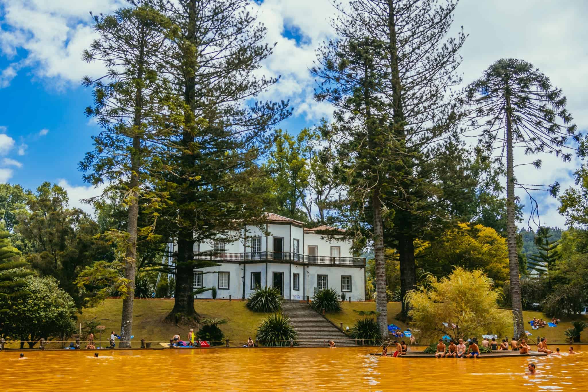 Turisté v termálním bazénu parku Terra Nostra s hnědavou vodou, Furnas, Azory